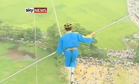Ķīniešu akrobāts noiet pa virvi starp diviem gaisa baloniem